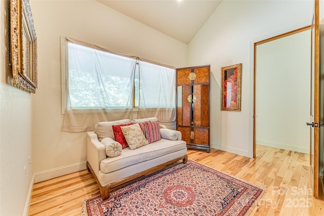 living area with vaulted ceiling, baseboards, and wood finished floors