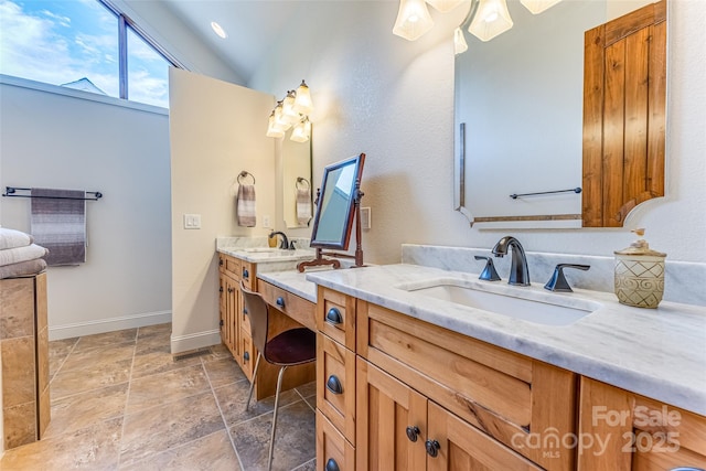 full bath featuring vaulted ceiling, vanity, baseboards, and stone finish flooring