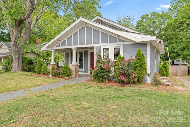 craftsman-style home with a porch, fence, and a front lawn
