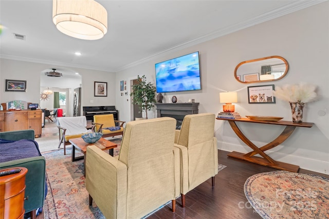 living room with visible vents, crown molding, wood finished floors, baseboards, and arched walkways