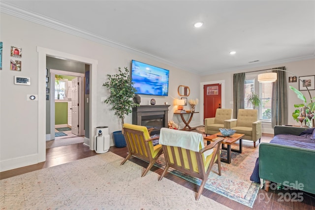 living area featuring baseboards, ornamental molding, plenty of natural light, and wood finished floors
