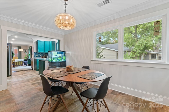 dining area with a chandelier, baseboards, visible vents, and light wood-style floors