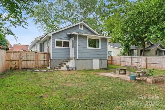 rear view of property with a lawn, a fenced backyard, and a patio area