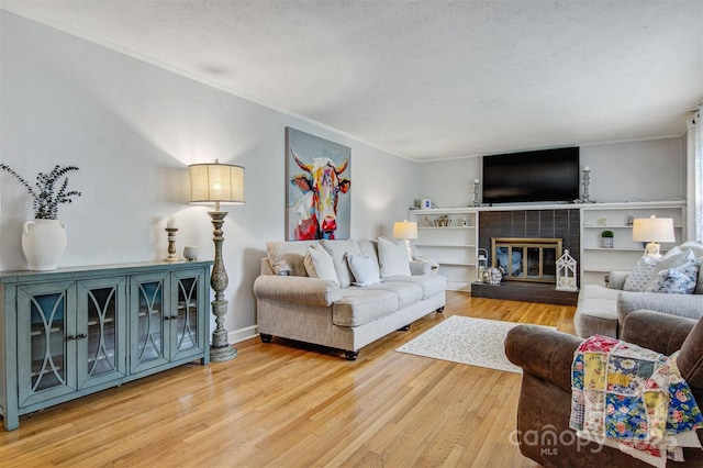 living room with crown molding, a textured ceiling, wood finished floors, and a tile fireplace