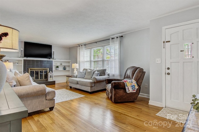 living area featuring ornamental molding, a tiled fireplace, and hardwood / wood-style flooring