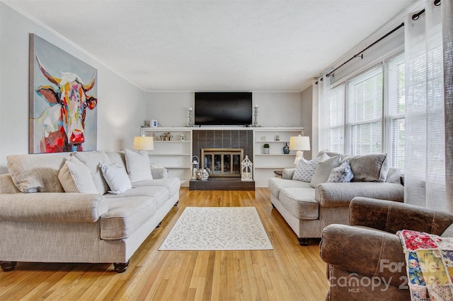living room featuring crown molding, a tiled fireplace, and wood finished floors