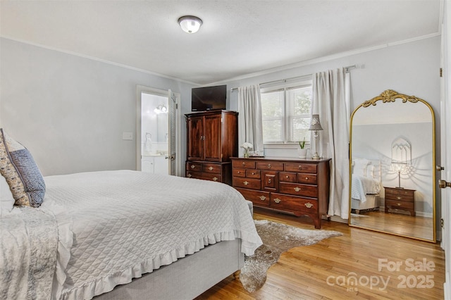 bedroom with crown molding, wood finished floors, and connected bathroom