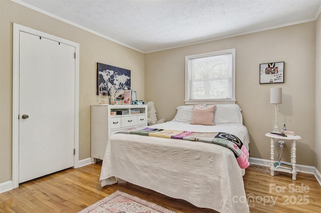 bedroom with crown molding, baseboards, a textured ceiling, and wood finished floors