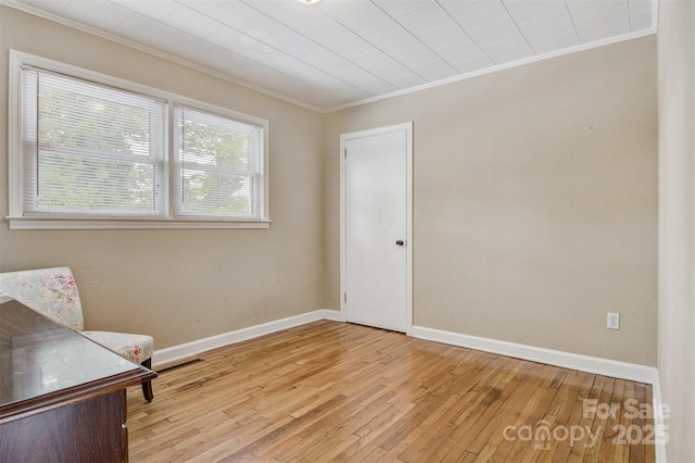 unfurnished room with light wood-style floors, baseboards, and ornamental molding
