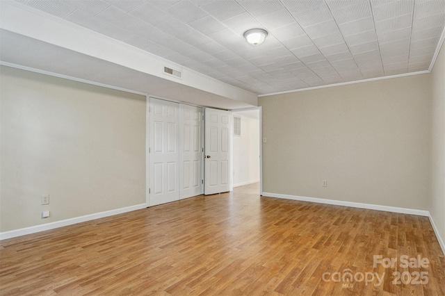 interior space with crown molding, baseboards, light wood-style flooring, and visible vents
