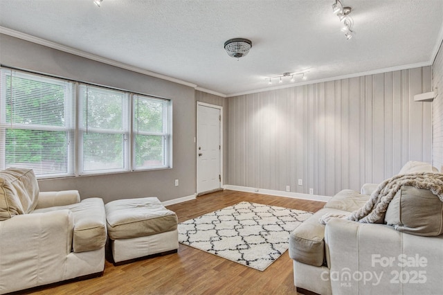living area with baseboards, ornamental molding, rail lighting, and wood finished floors
