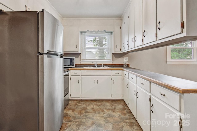 kitchen featuring plenty of natural light, a sink, appliances with stainless steel finishes, and stone finish floor