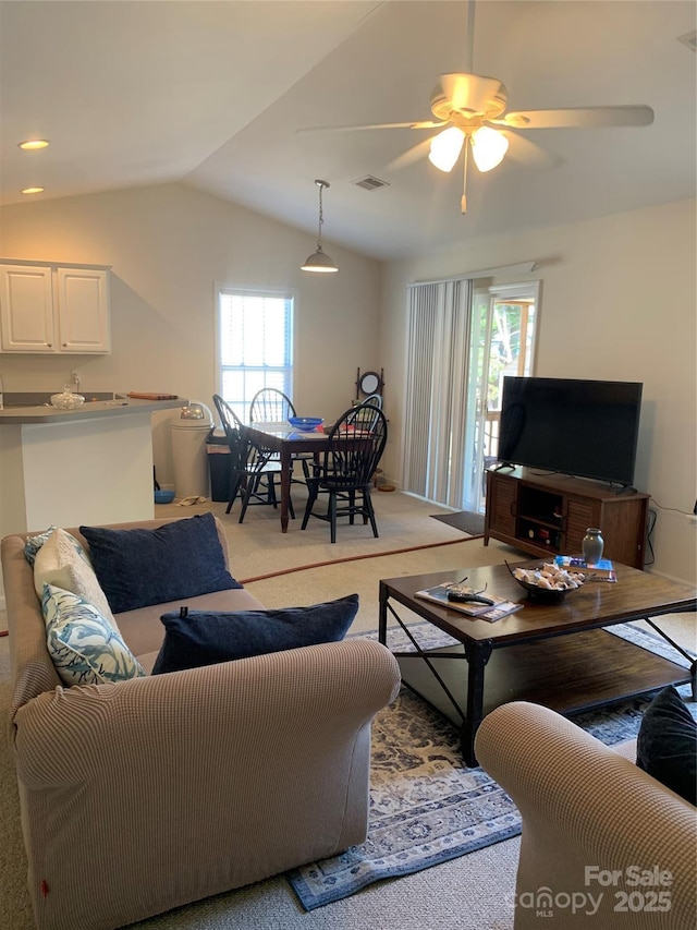 living area with vaulted ceiling, visible vents, ceiling fan, and light carpet
