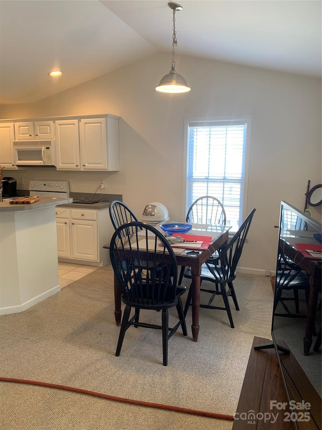 dining space featuring baseboards, light carpet, and vaulted ceiling