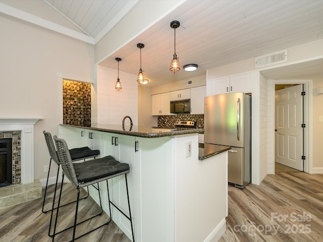 kitchen featuring visible vents, light wood-style flooring, appliances with stainless steel finishes, and a kitchen bar