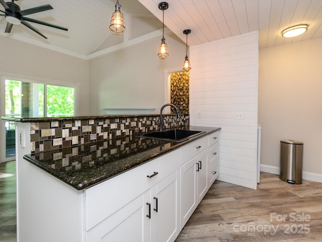kitchen featuring ceiling fan, light wood-type flooring, white cabinetry, a sink, and backsplash