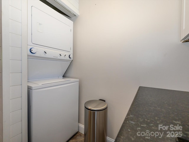 washroom with laundry area, stacked washer and clothes dryer, and baseboards