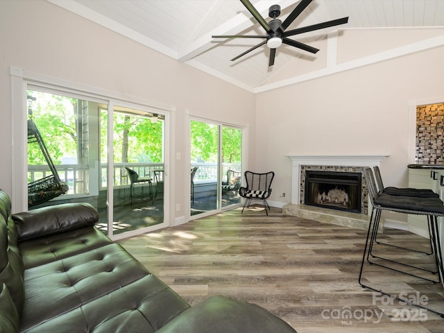 living area featuring beam ceiling, a premium fireplace, high vaulted ceiling, a ceiling fan, and wood finished floors