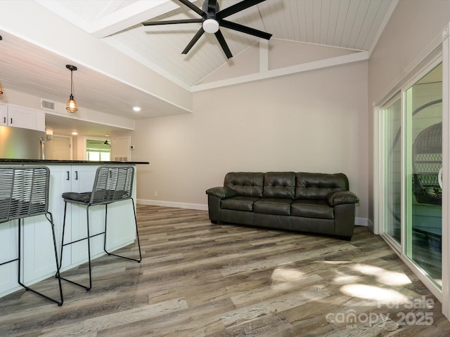 living area with a ceiling fan, baseboards, vaulted ceiling with beams, wood finished floors, and visible vents