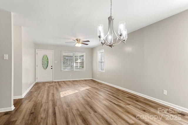 entrance foyer with baseboards, ceiling fan with notable chandelier, and wood finished floors