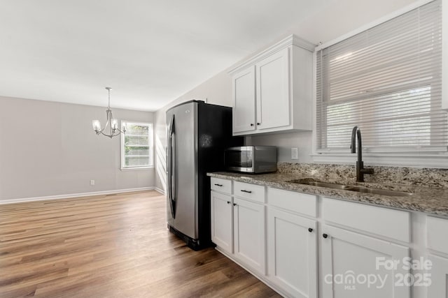 kitchen with light wood-style flooring, a sink, a chandelier, white cabinets, and appliances with stainless steel finishes