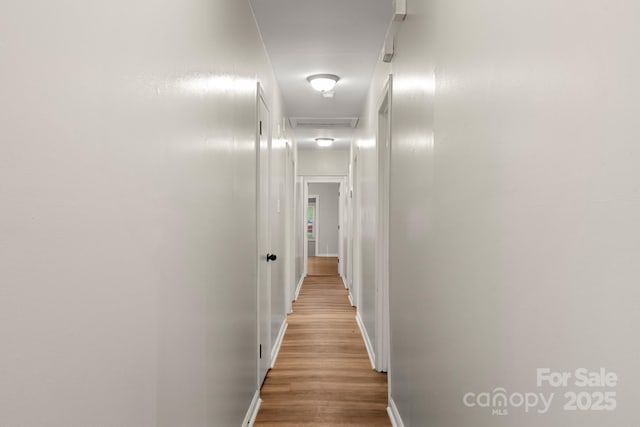 hallway featuring baseboards and wood finished floors