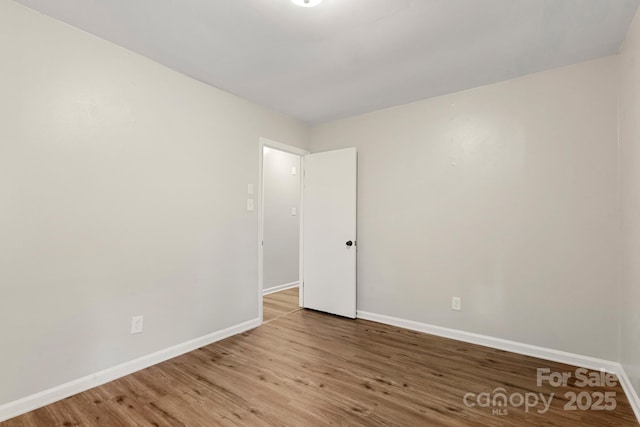 spare room with baseboards and wood finished floors