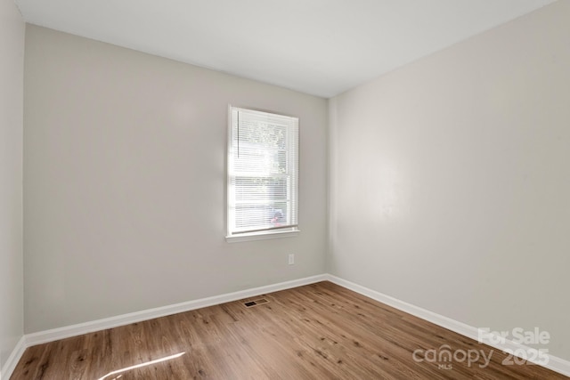 empty room with visible vents, wood finished floors, and baseboards