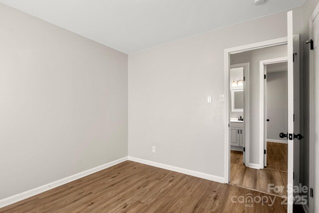 unfurnished bedroom with a sink, baseboards, and wood finished floors