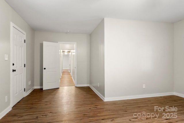 spare room with baseboards and wood finished floors
