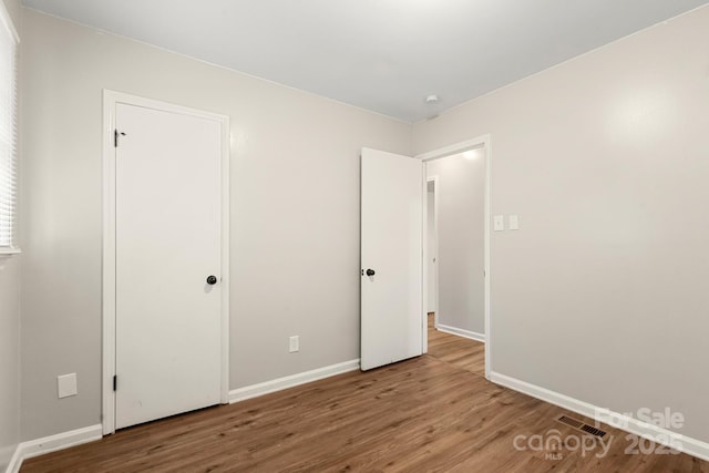 unfurnished bedroom with visible vents, wood finished floors, and baseboards