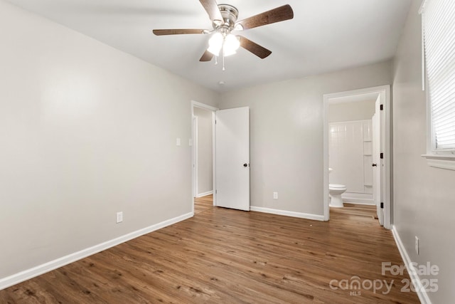 unfurnished bedroom featuring ceiling fan, ensuite bath, baseboards, and wood finished floors