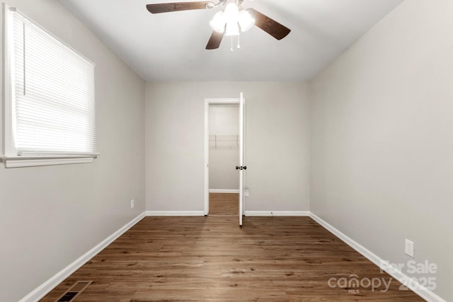 unfurnished room featuring baseboards, wood finished floors, a ceiling fan, and visible vents