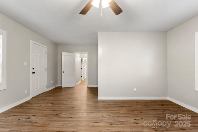 empty room featuring baseboards, a ceiling fan, and wood finished floors
