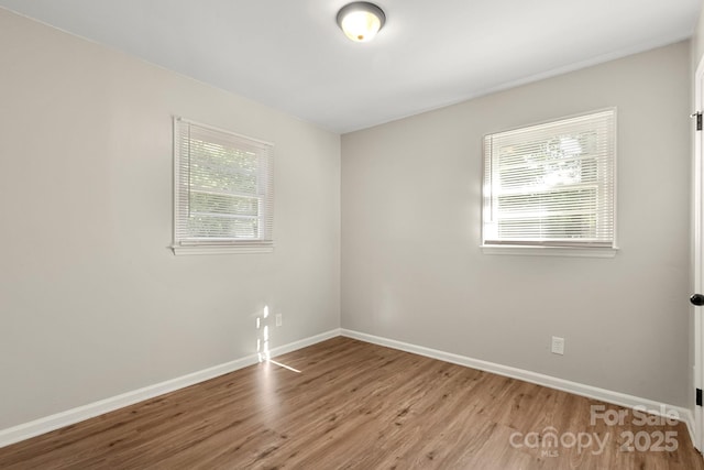 spare room with baseboards and wood finished floors