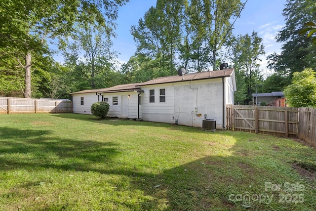 back of property with a fenced backyard, central air condition unit, brick siding, and a lawn