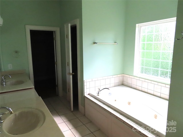 bathroom with a tub with jets, tile patterned floors, double vanity, and a sink