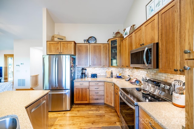 958 Alta Vista Ln, Sparta, NC 28675 - kitchen with stainless steel appliances, decorative backsplash, glass insert cabinets, and light wood finished floors