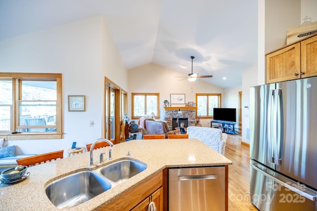 958 Alta Vista Ln, Sparta, NC 28675 - kitchen featuring appliances with stainless steel finishes, vaulted ceiling, a sink, light stone counters, and light wood-style flooring