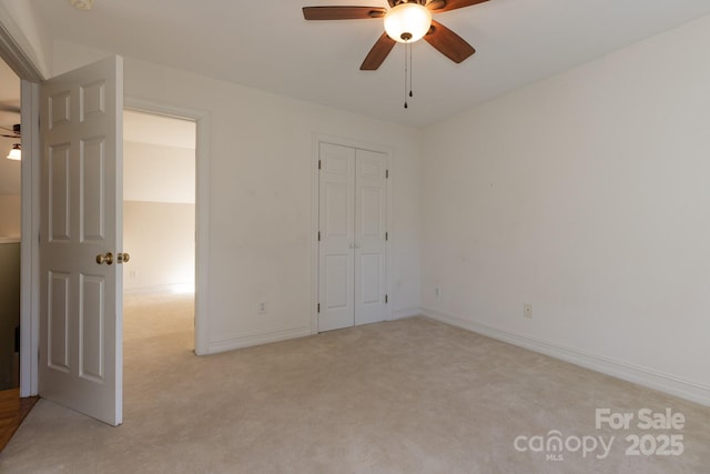 unfurnished bedroom featuring a closet, baseboards, a ceiling fan, and light colored carpet