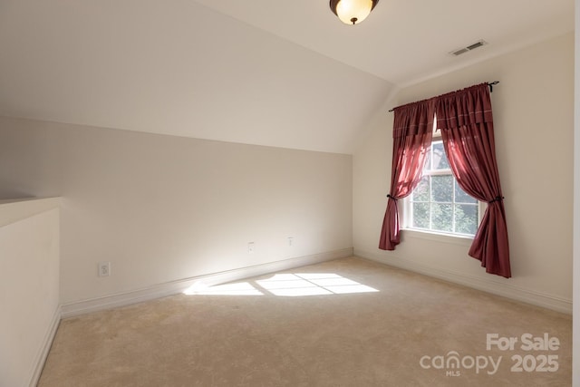 additional living space with carpet floors, baseboards, visible vents, and vaulted ceiling