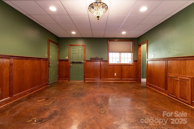 unfurnished room featuring concrete flooring, wood walls, recessed lighting, and a wainscoted wall