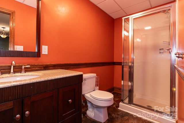 bathroom with vanity, a shower stall, toilet, and a paneled ceiling