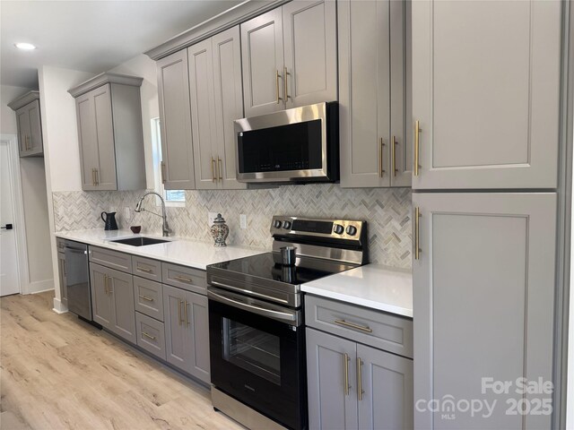 3114 Ansonville Rd, Marshville, NC 28103 - kitchen featuring appliances with stainless steel finishes, gray cabinetry, a sink, light wood-style flooring, and recessed lighting