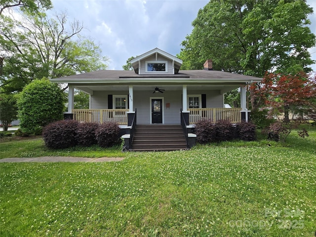 bungalow-style house with a chimney, a porch, and a front lawn