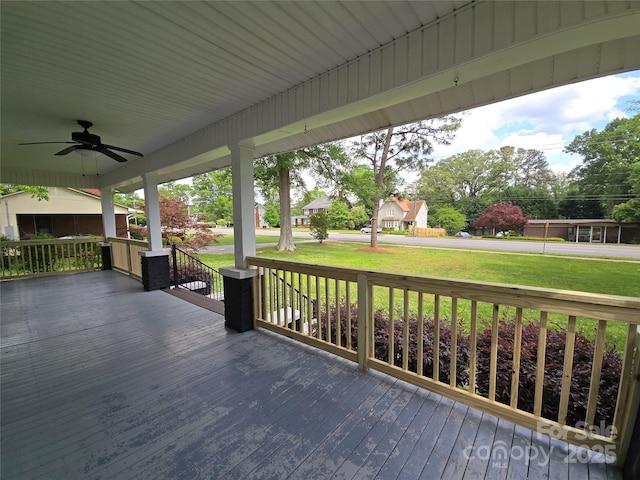 deck featuring ceiling fan, a yard, and covered porch