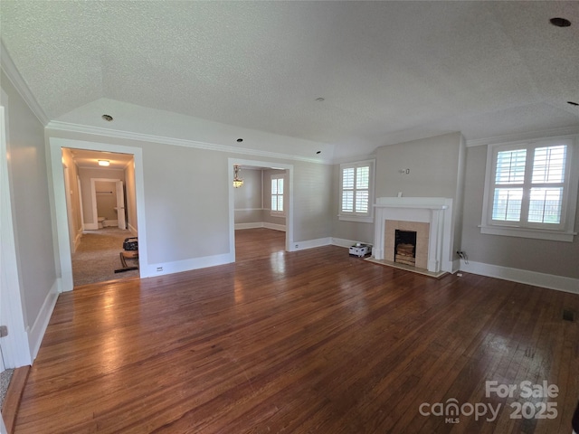 unfurnished living room with crown molding, a textured ceiling, baseboards, a fireplace with flush hearth, and hardwood / wood-style flooring