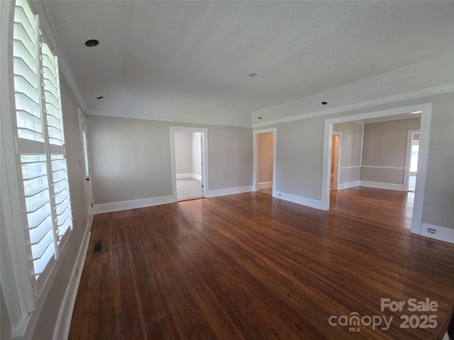 spare room with visible vents, ornamental molding, wood finished floors, baseboards, and a textured ceiling