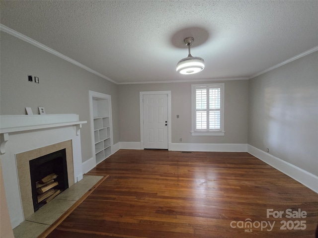 unfurnished living room featuring ornamental molding, a textured ceiling, wood finished floors, and built in shelves