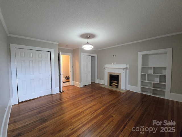 unfurnished living room featuring crown molding, a textured ceiling, built in features, wood finished floors, and a tile fireplace